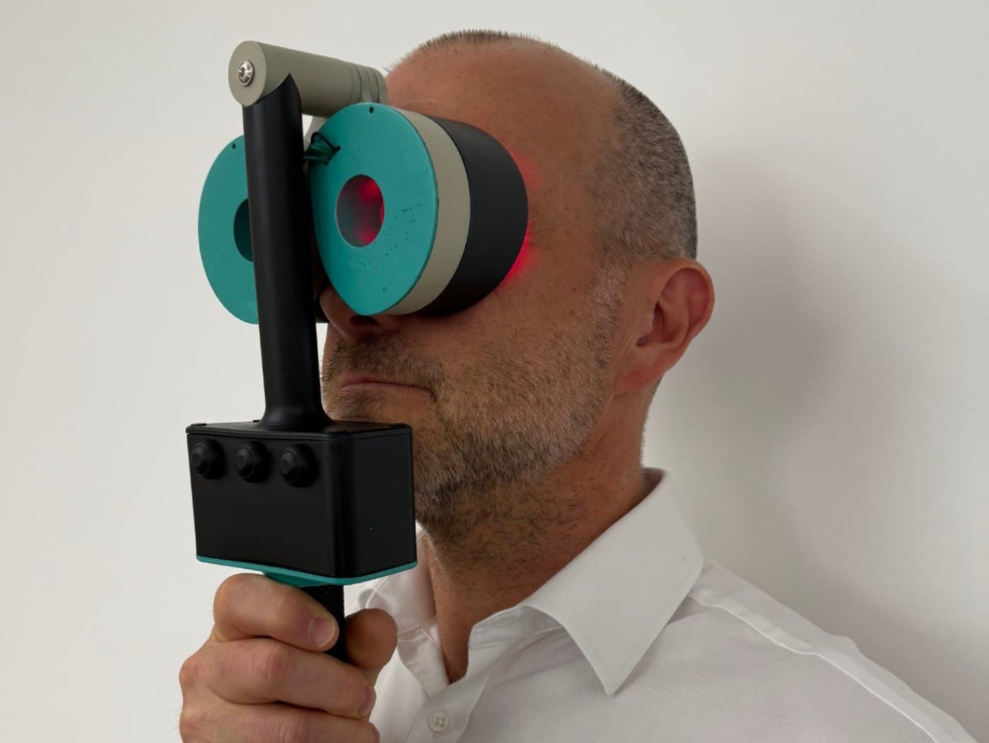 The Revolux photobiomodulation device held up to the eyes, with red therapy light visible around the eyecups